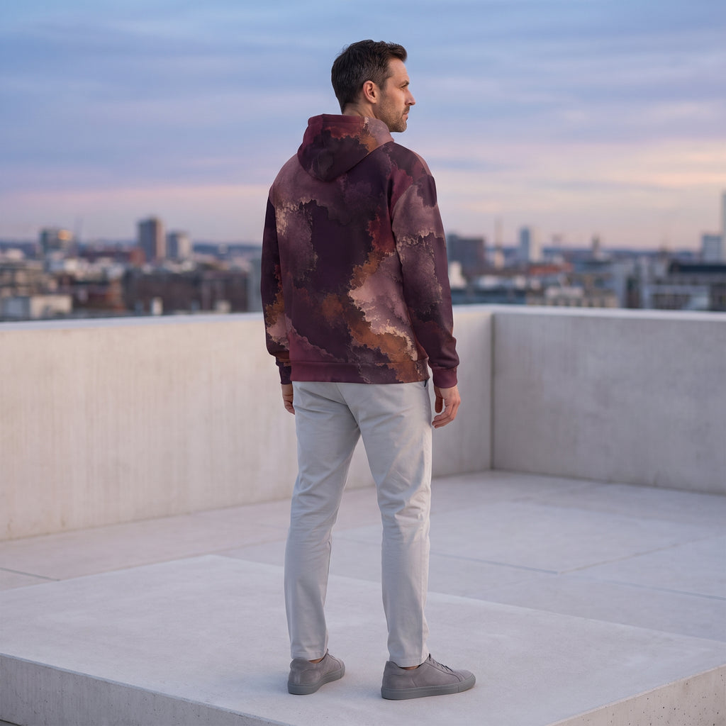 Man wearing the Ember Eclipse hoodie on a rooftop – burgundy, plum and copper abstract print