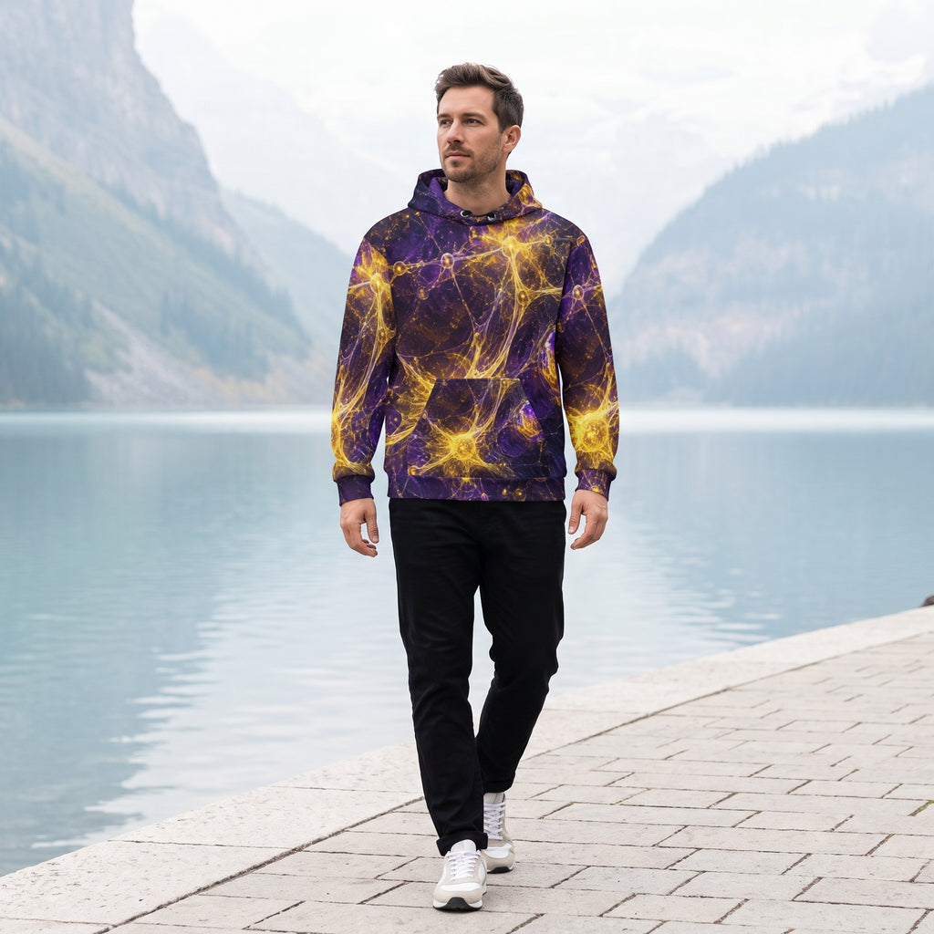 A man walking along a paved path next to a calm lake with mountains in the background, wearing a purple and yellow cosmic nebula print hoodie, black pants, and white sneakers.