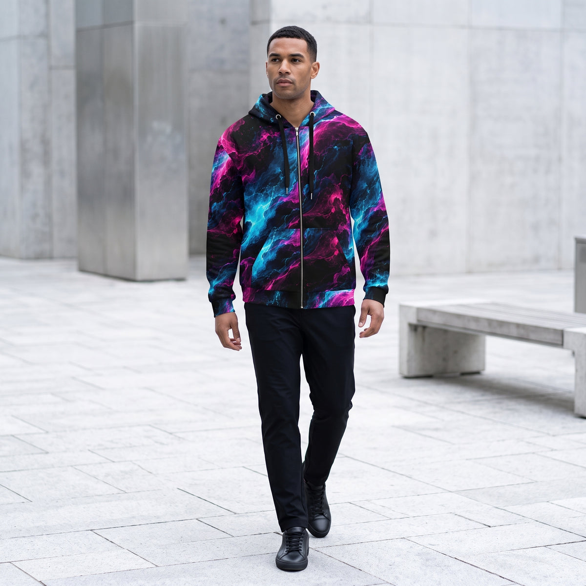 Model walking in the Neon Vortex zip hoodie in an urban plaza – cyan, magenta and black nebula print
