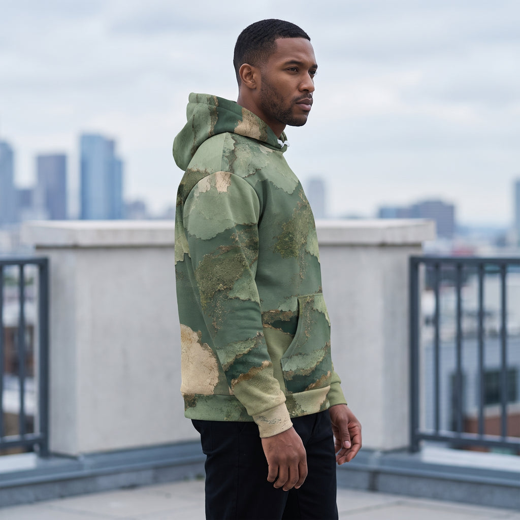 Model wearing the Verdant Terrain hoodie on a rooftop – sage, olive and gold abstract print