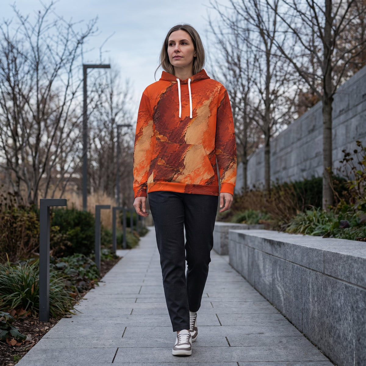 Model wearing the Ember Terrain hoodie – burnt orange, rust and brown earth-tone print
