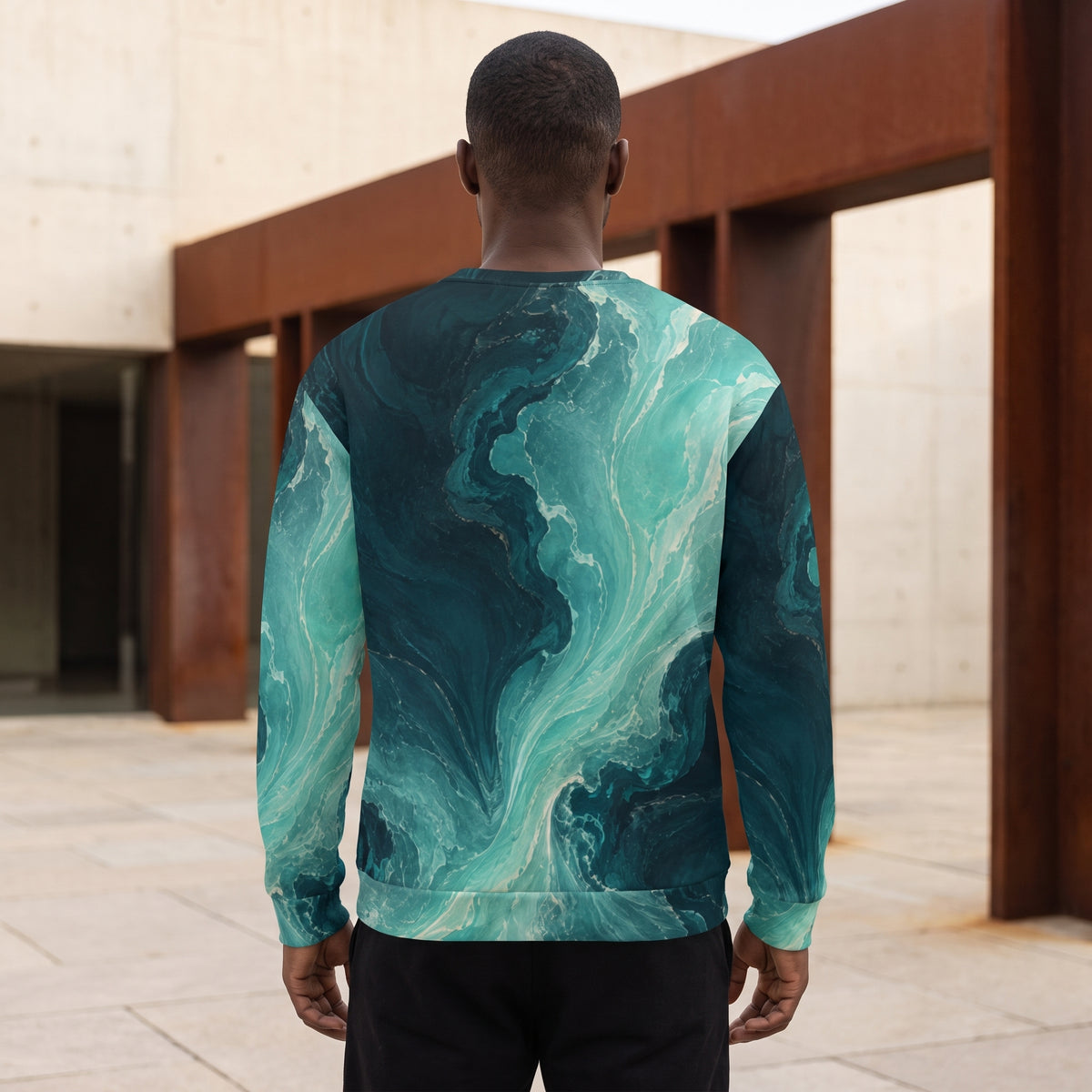 A man viewed from behind wearing a long-sleeve crewneck sweatshirt with a teal and dark blue marble wave pattern, set against a modern architectural background.