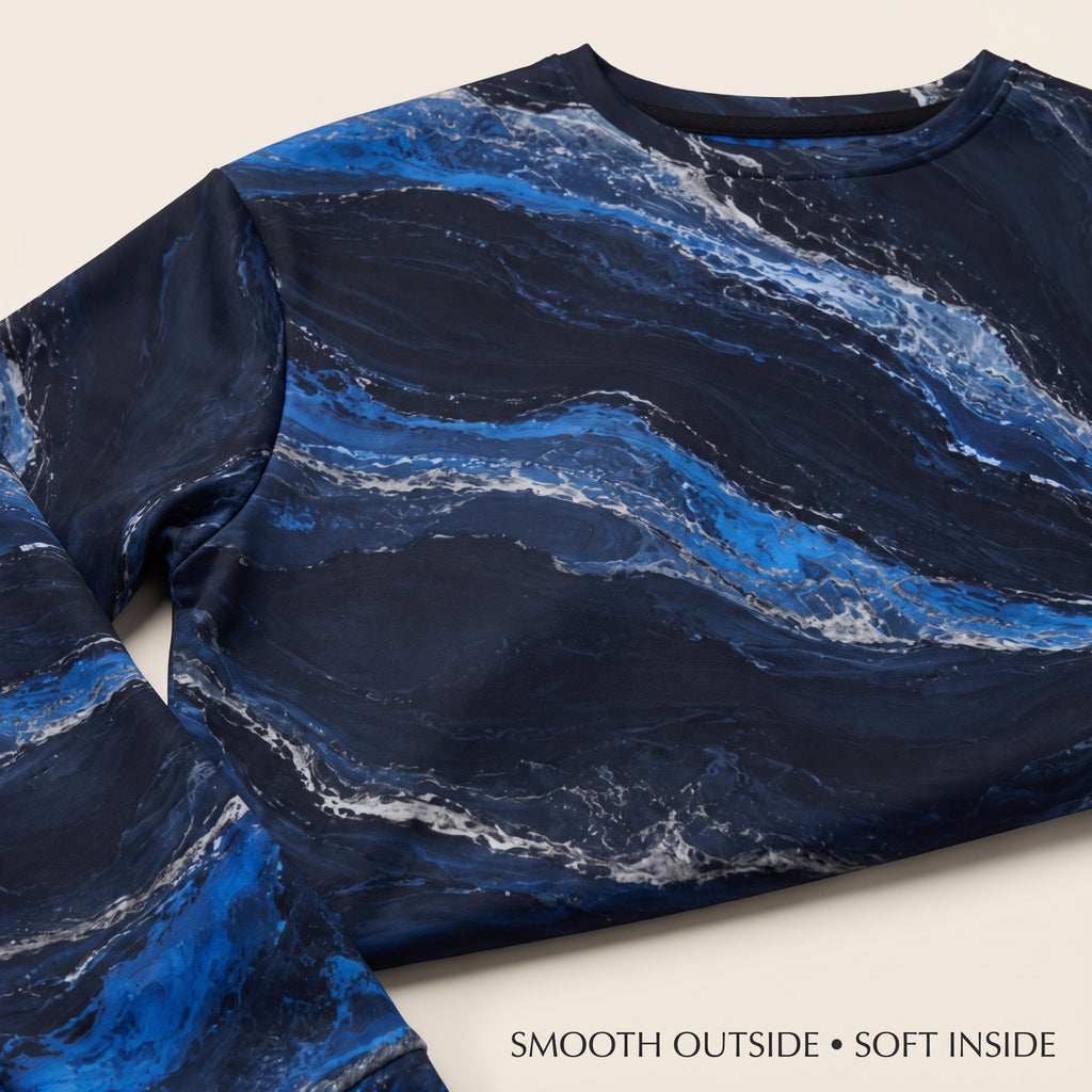 A close-up of a long-sleeve crewneck top with a dark navy and bright blue marble pattern, featuring white veining. Text at the bottom reads 'SMOOTH OUTSIDE • SOFT INSIDE'.