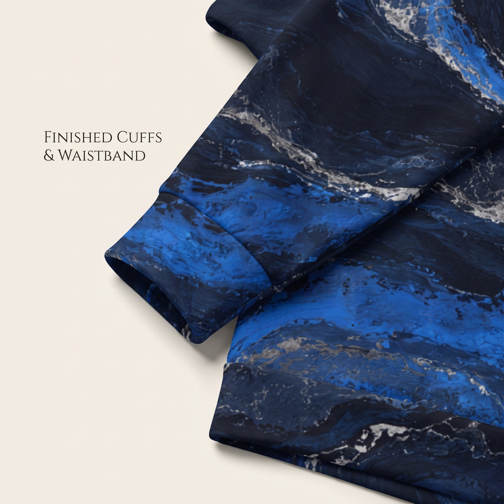 A close-up of a garment sleeve with a blue and navy marble pattern, showing finished cuffs and waistband details, on a light beige background with text reading 'FINISHED CUFFS & WAISTBAND'.