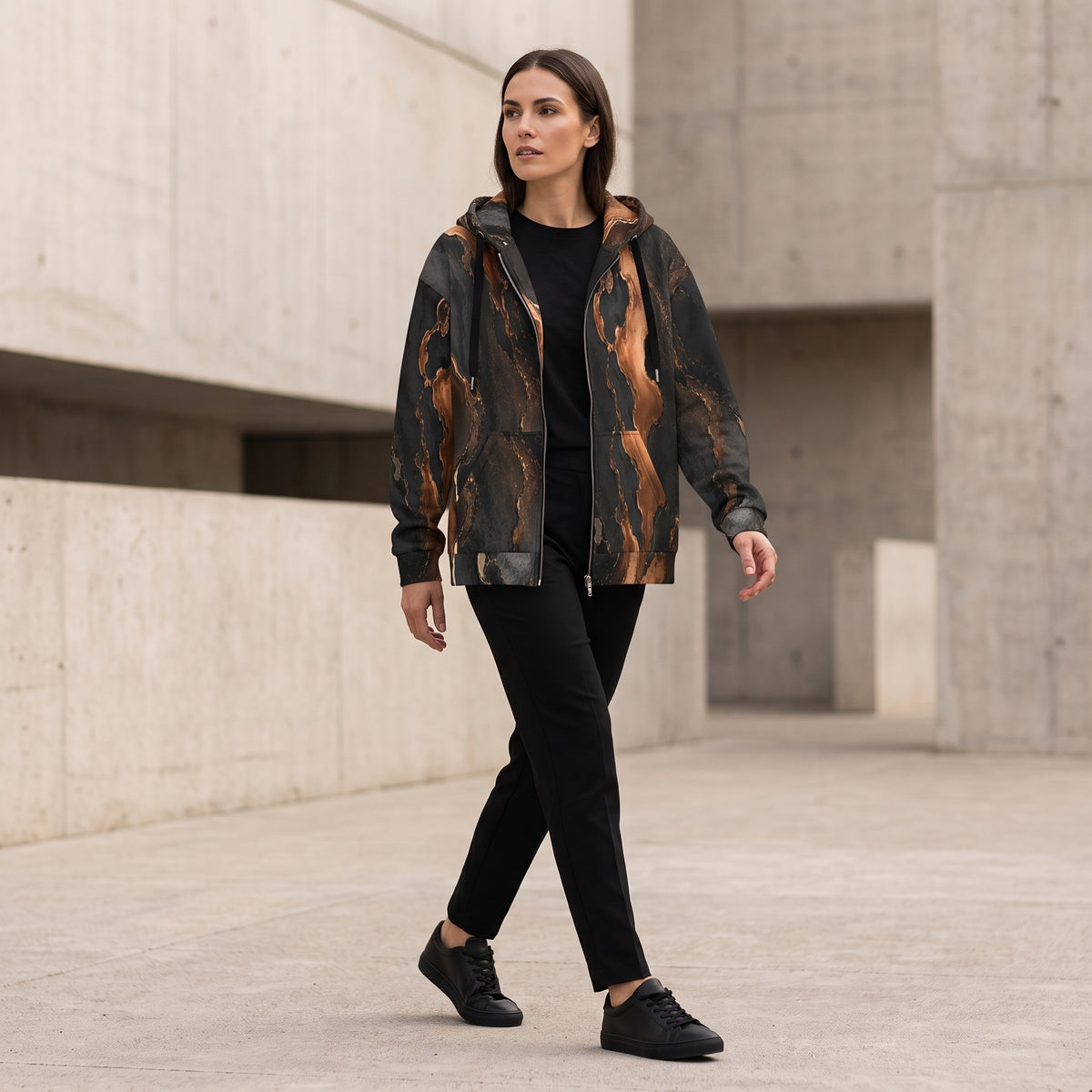 Woman walking in the Molten Ember zip hoodie – black and copper abstract print